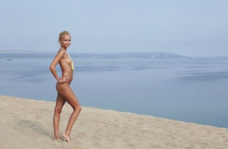 Гибкая девушка позирует голой на пляже