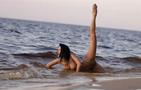 Гибкая голая девушка на берегу моря