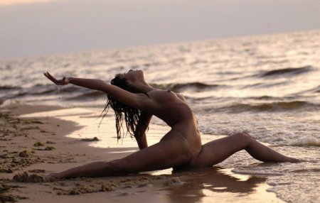 Гибкая голая девушка на берегу моря